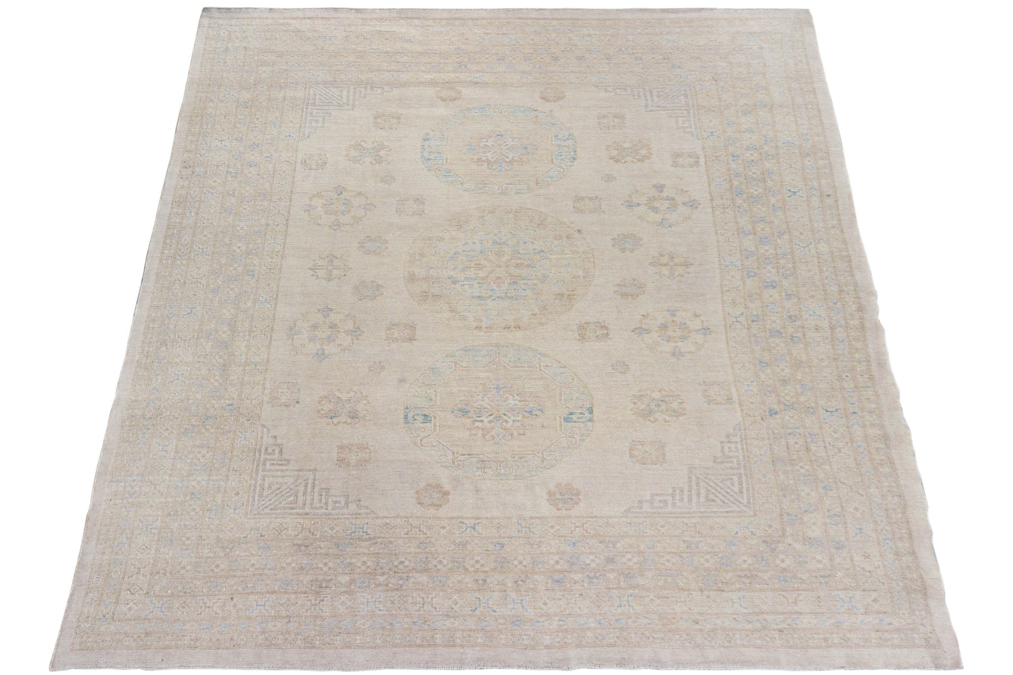 A handmade Afghan Chobi rug featuring a neutral beige palette with subtle blue medallion patterns.