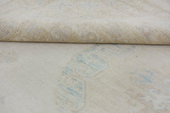 A close-up of a handmade Afghan Chobi rug featuring a light beige wool pile with blue patterns.