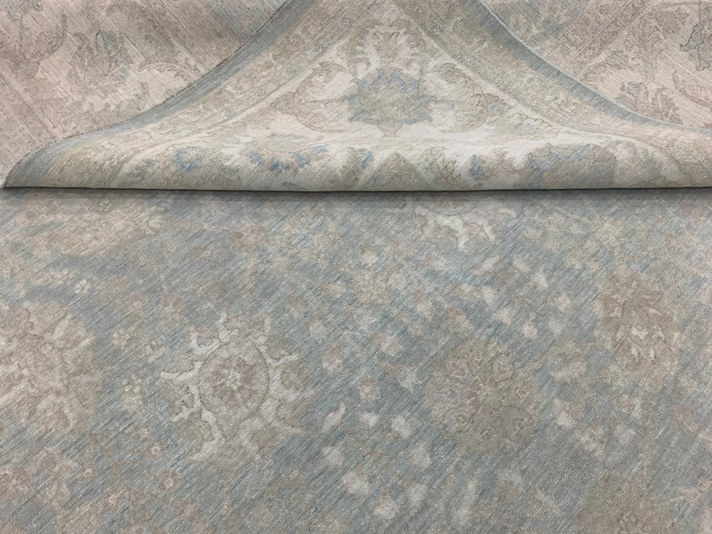 A handmade Afghan Chobi rug featuring a traditional floral pattern in soft blue and beige tones.