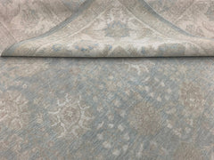 A handmade Afghan Chobi rug featuring a traditional floral pattern in soft blue and beige tones.