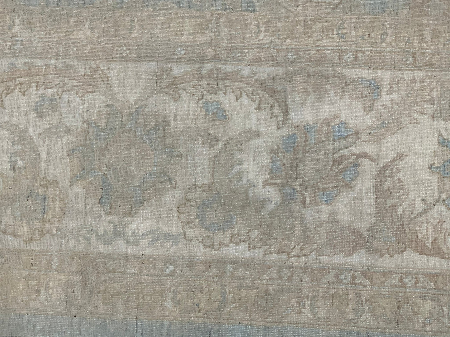 A handmade Afghan Chobi rug featuring a traditional floral pattern in muted beige and blue tones.