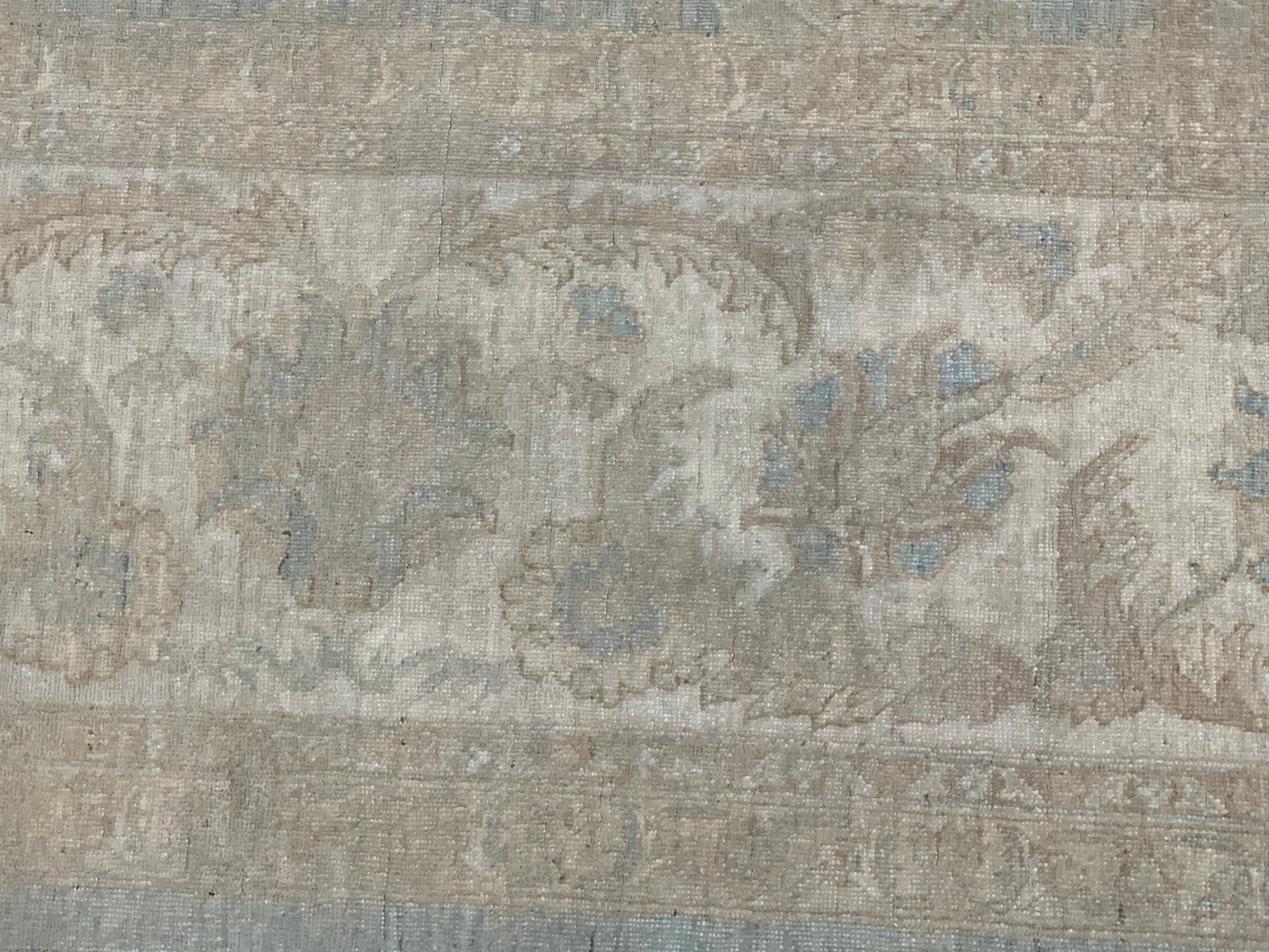 A handmade Afghan Chobi rug featuring a traditional floral pattern in muted beige and blue tones.