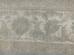 A handmade Afghan Chobi rug featuring a traditional floral pattern in muted beige and blue tones.