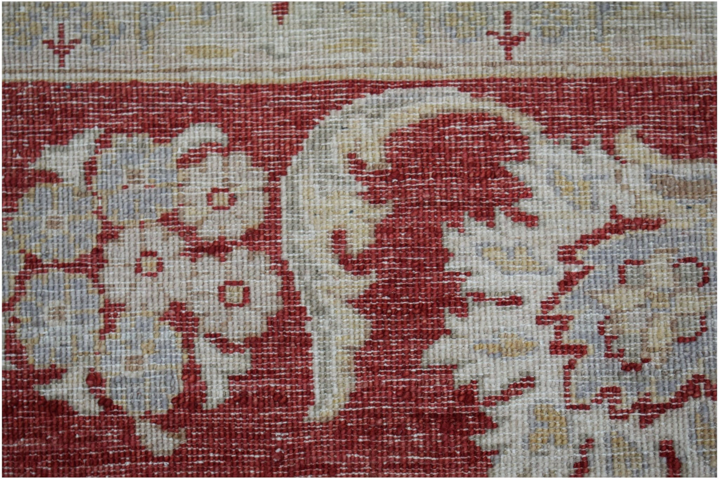 A close-up of an Afghan Chobi rug featuring intricate floral patterns in red, cream, and grey.
