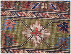 A close-up of an Afghan Chobi rug featuring a green field with a central floral motif and borders.