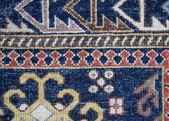 A close-up view of a handwoven Afghan Chobi rug featuring intricate geometric patterns in blue, gold, and rust tones.