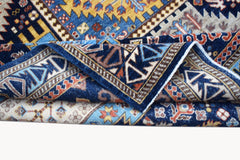 A folded Afghan Chobi rug featuring intricate geometric patterns in blue, yellow, and cream tones.