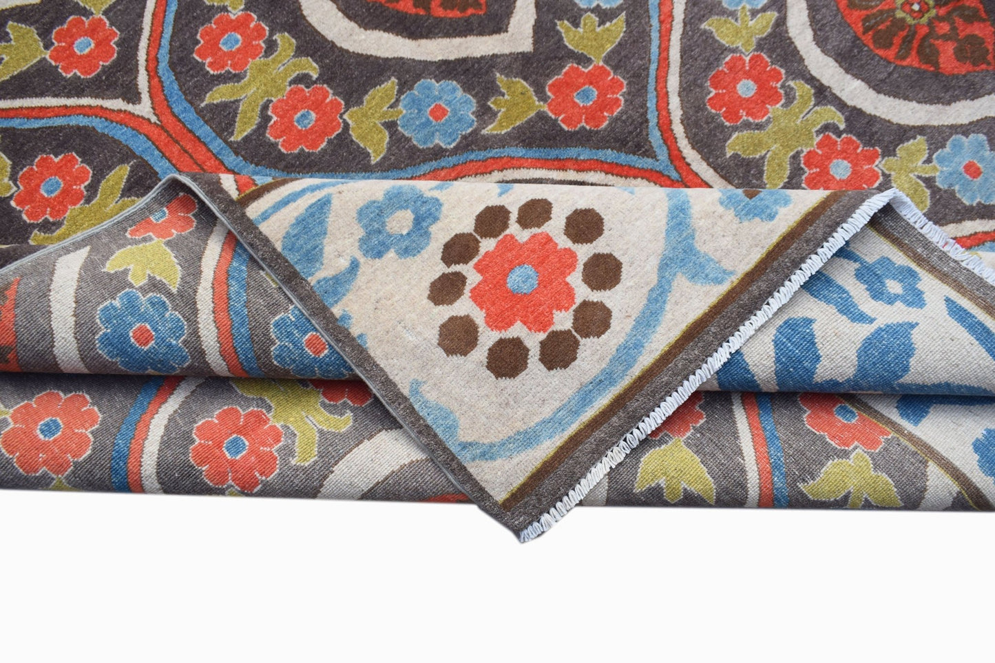 A handmade Afghan Chobi rug featuring a floral pattern in red, blue, and green on a dark background.