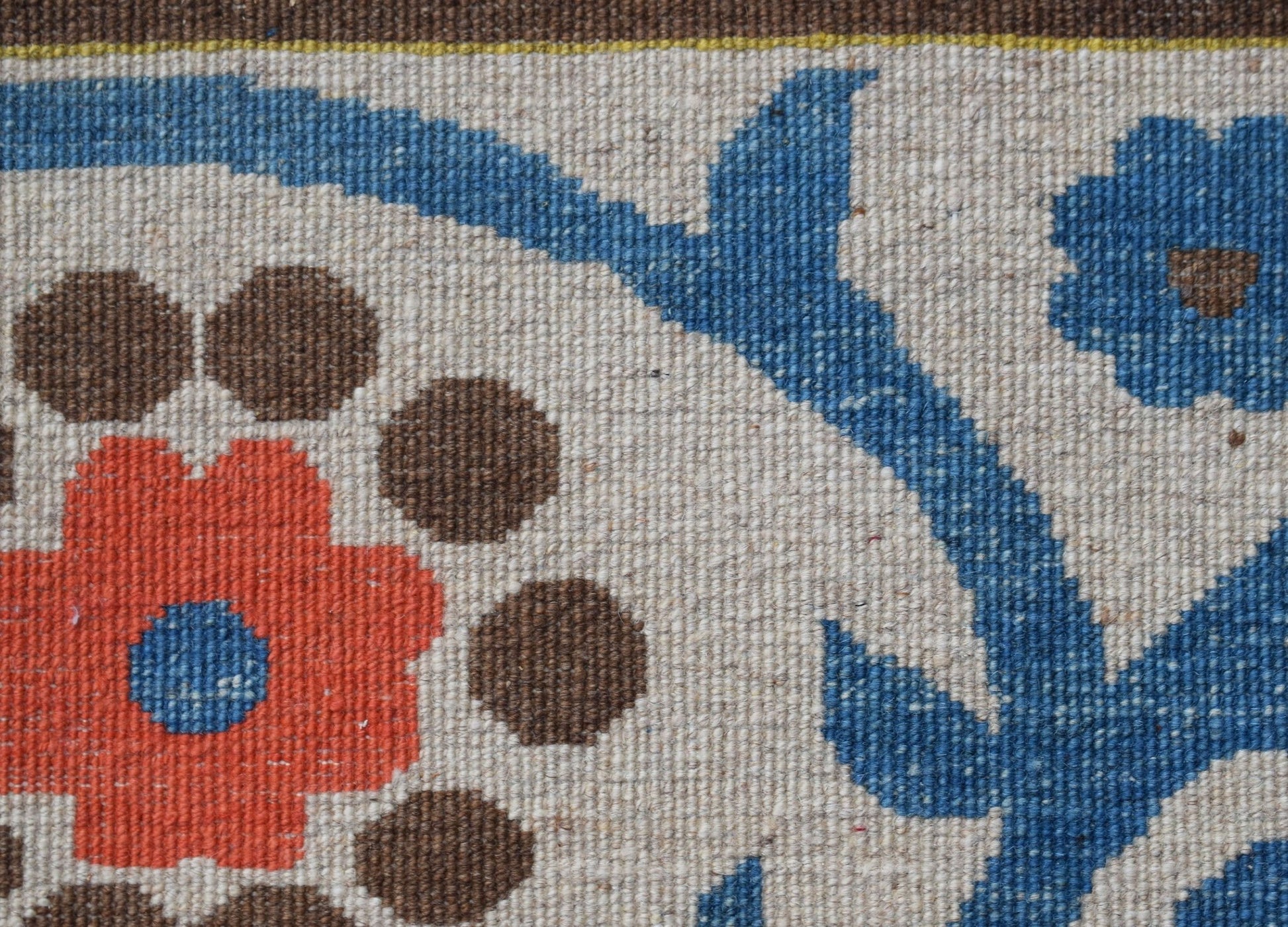 A close-up of a handwoven Afghan Chobi rug featuring a floral pattern in blue, orange, and brown.