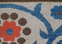 A close-up of a handwoven Afghan Chobi rug featuring a floral pattern in blue, orange, and brown.