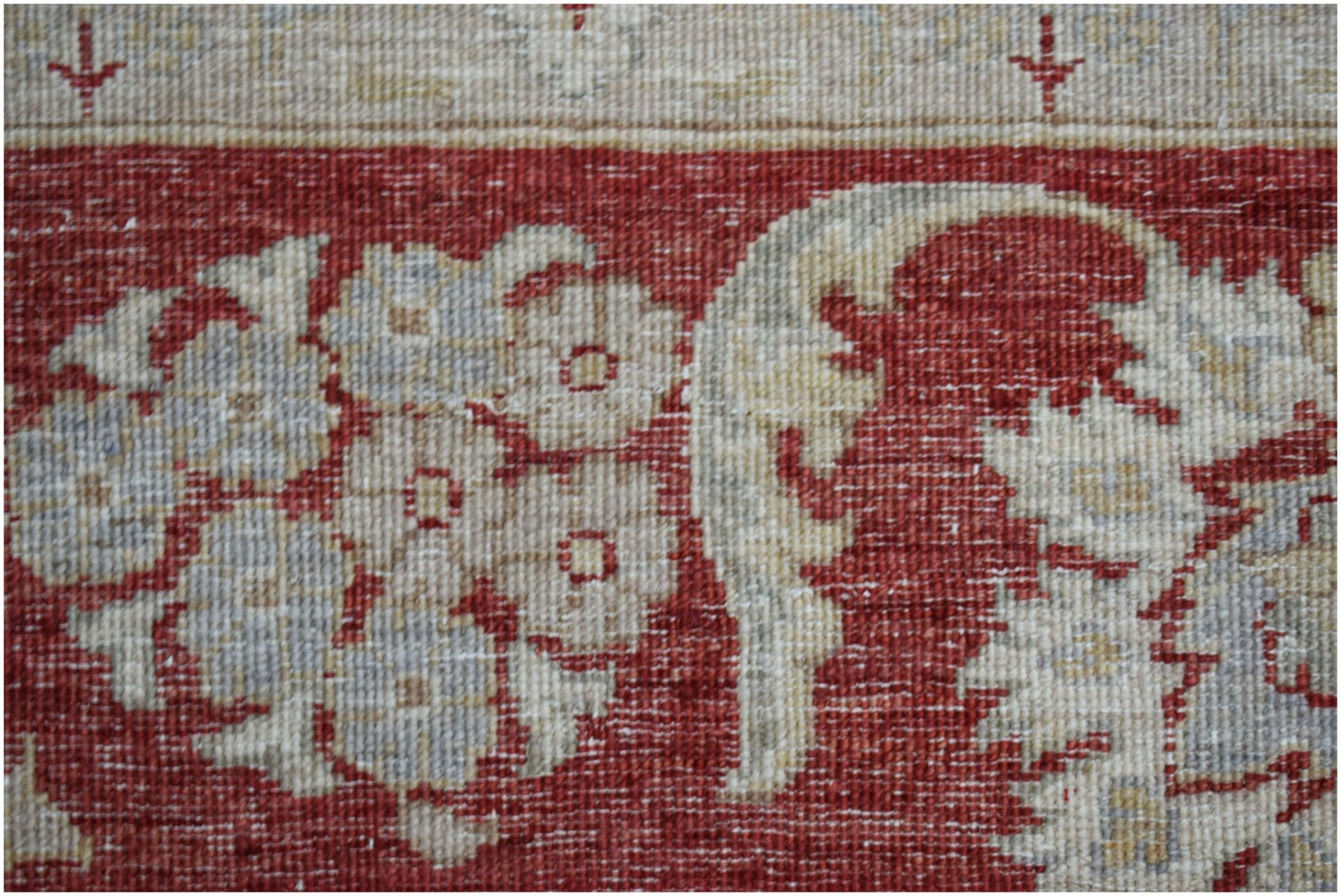 A close-up of an Afghan Chobi rug featuring intricate floral patterns in muted tones on a red field.