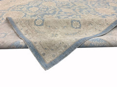 A handmade Afghan Chobi rug featuring a traditional floral pattern in soft blue and beige tones.