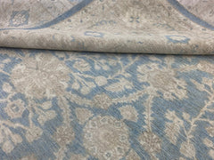 A handmade Afghan Chobi rug featuring a traditional floral pattern in soft blue and beige tones.