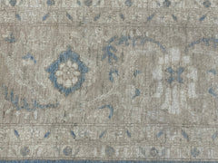 A handmade Afghan Chobi rug featuring a traditional floral pattern in muted blue and beige tones.