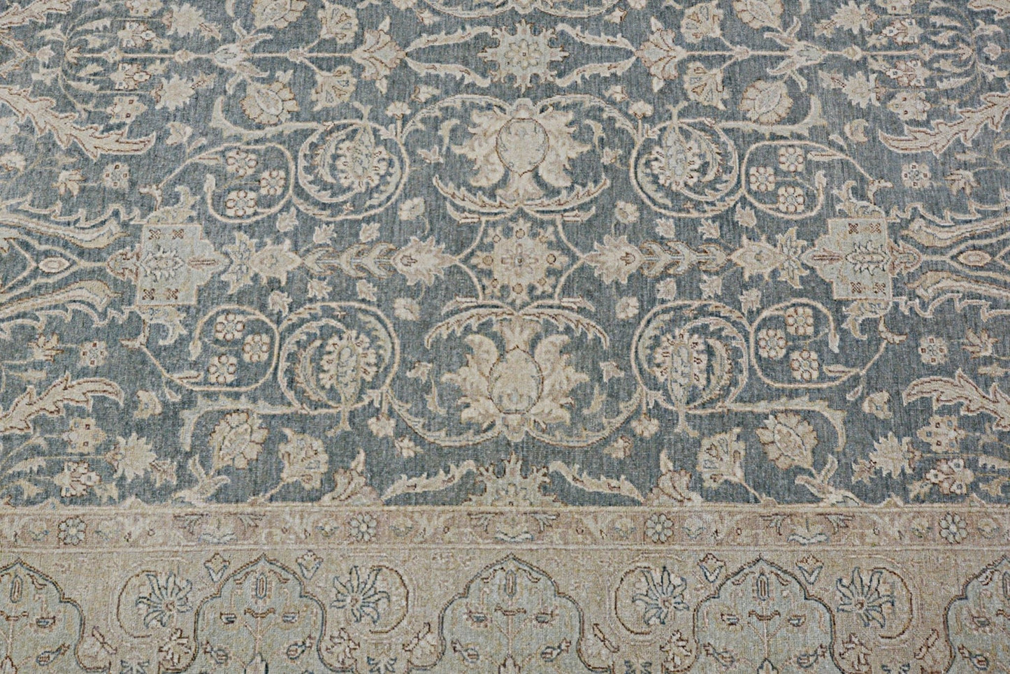 A handmade Afghan Chobi rug featuring intricate floral patterns in muted blue and beige tones.