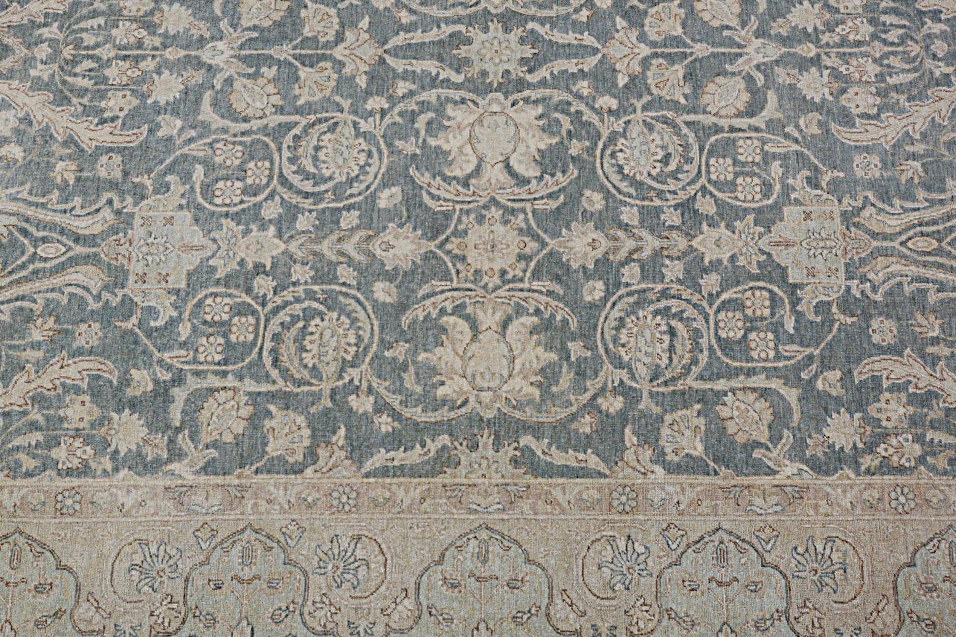 A handmade Afghan Chobi rug featuring intricate floral patterns in muted blue and beige tones.