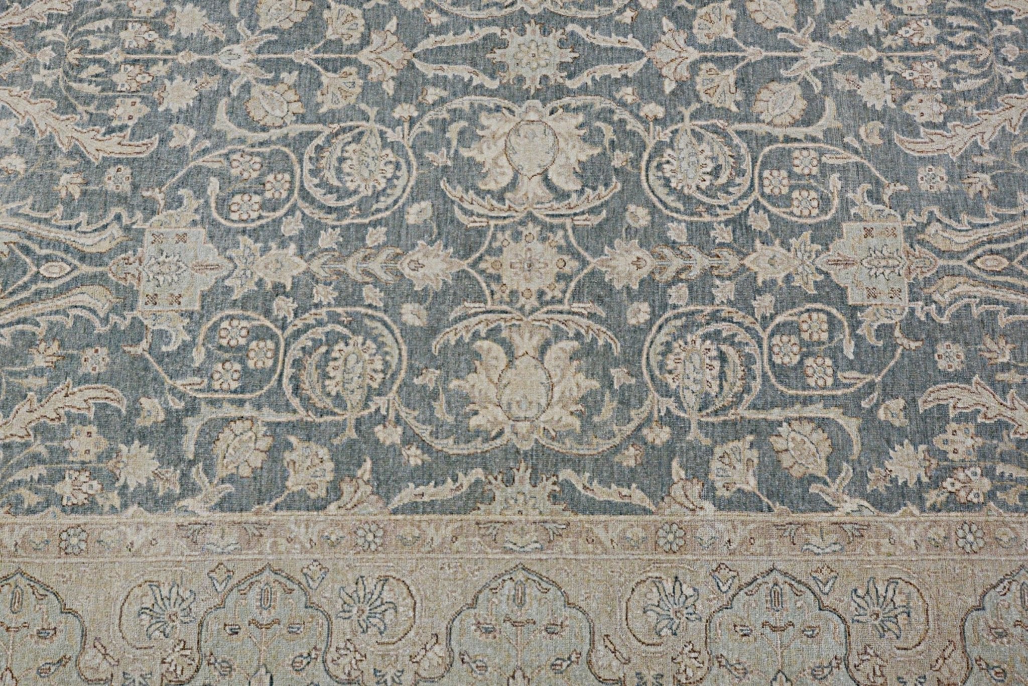 A handmade Afghan Chobi rug featuring intricate floral patterns in muted blue and beige tones.