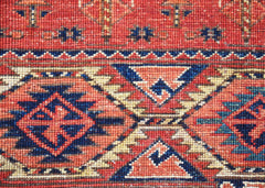 A close-up of a handwoven Afghan Chobi rug featuring traditional geometric patterns in red and blue.