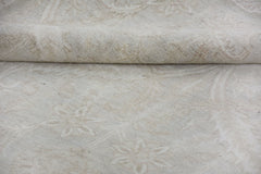 A close-up of a handmade Afghan Chobi rug featuring a subtle, light-toned floral pattern.