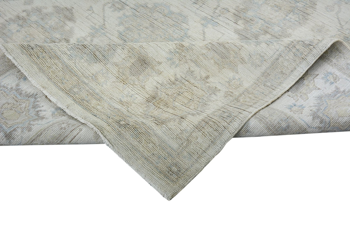 A handmade Afghan Chobi rug with a folded corner showing its light-toned wool texture.