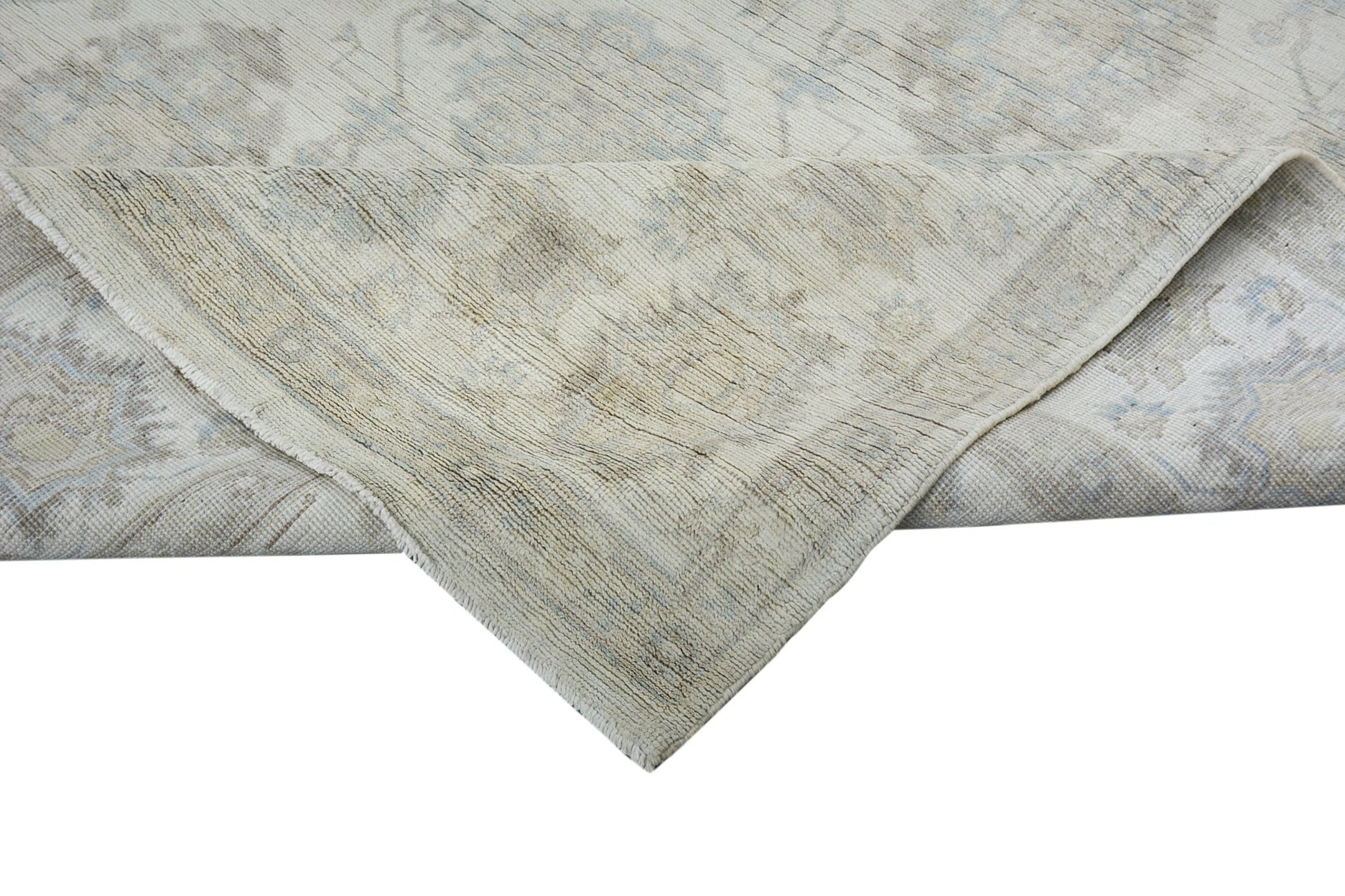A handmade Afghan Chobi rug with a folded corner showing its light-toned wool texture.