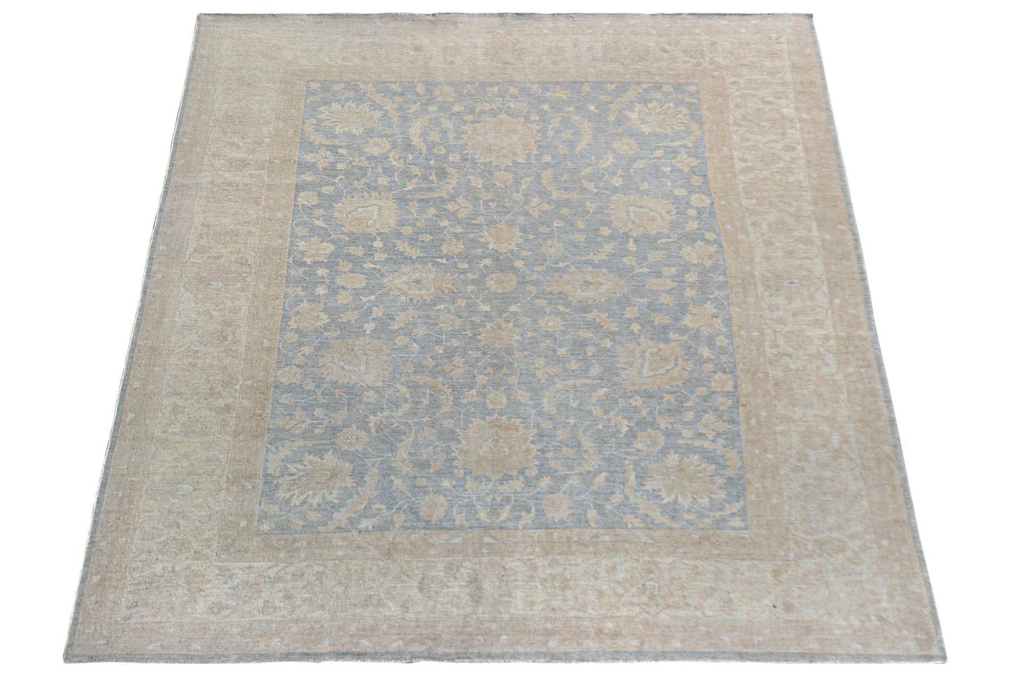 A handmade Afghan Chobi rug featuring a light blue central field with beige floral patterns.