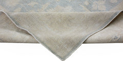 A corner of a handmade Afghan Chobi rug showing its light blue and beige wool pile and backing.