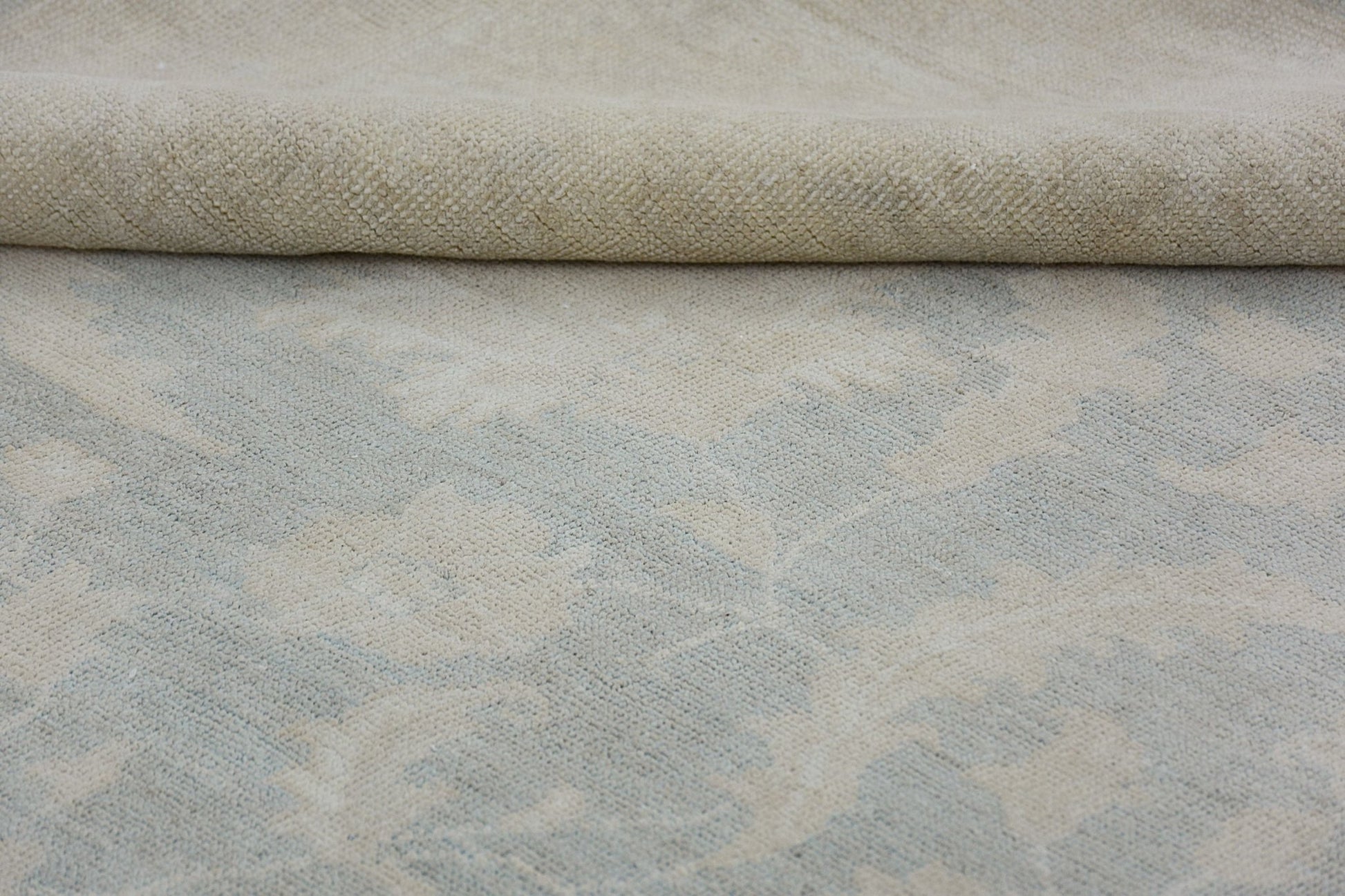 A close-up view of a handmade Afghan Chobi rug featuring a soft, neutral floral pattern.