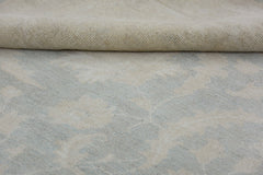 A close-up view of a handmade Afghan Chobi rug featuring a soft, neutral floral pattern.