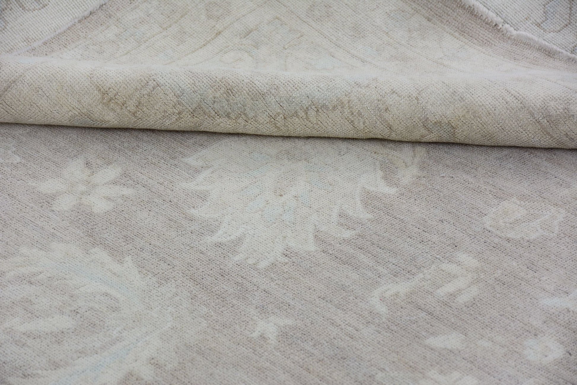 A handmade Afghan Chobi rug featuring a neutral, monochromatic floral pattern on handspun wool.