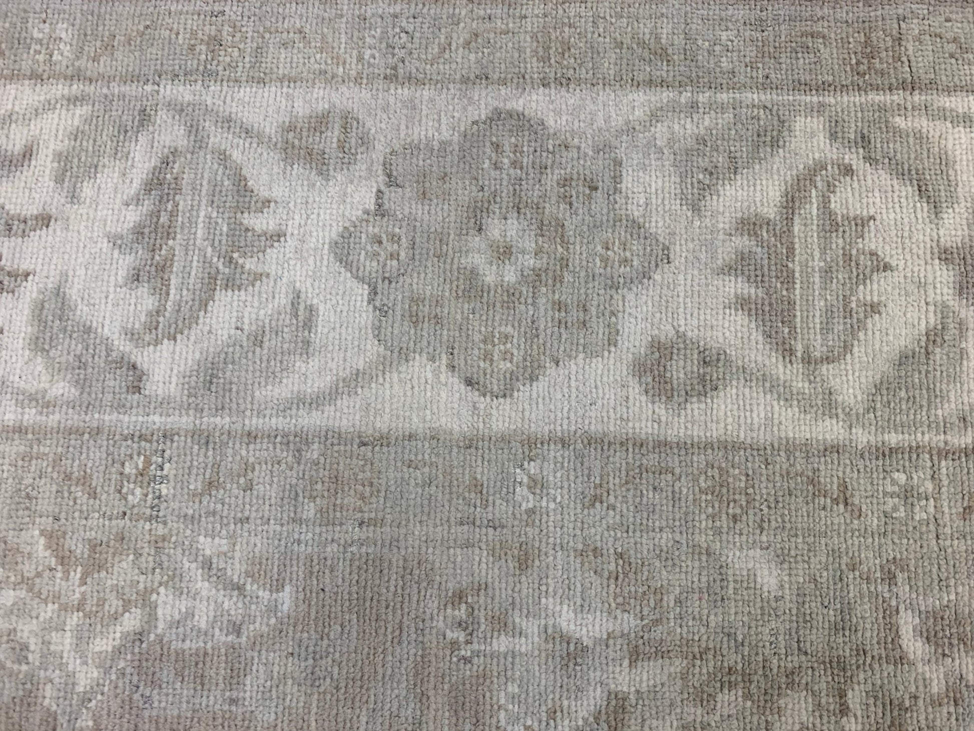 A handmade Afghan Chobi rug featuring a traditional floral pattern in neutral beige and grey tones.