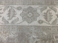 A handmade Afghan Chobi rug featuring a traditional floral pattern in neutral beige and grey tones.