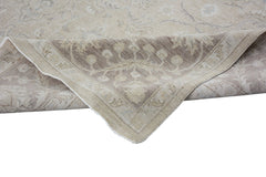 A folded Afghan Chobi rug featuring a traditional floral pattern in neutral beige and brown tones.