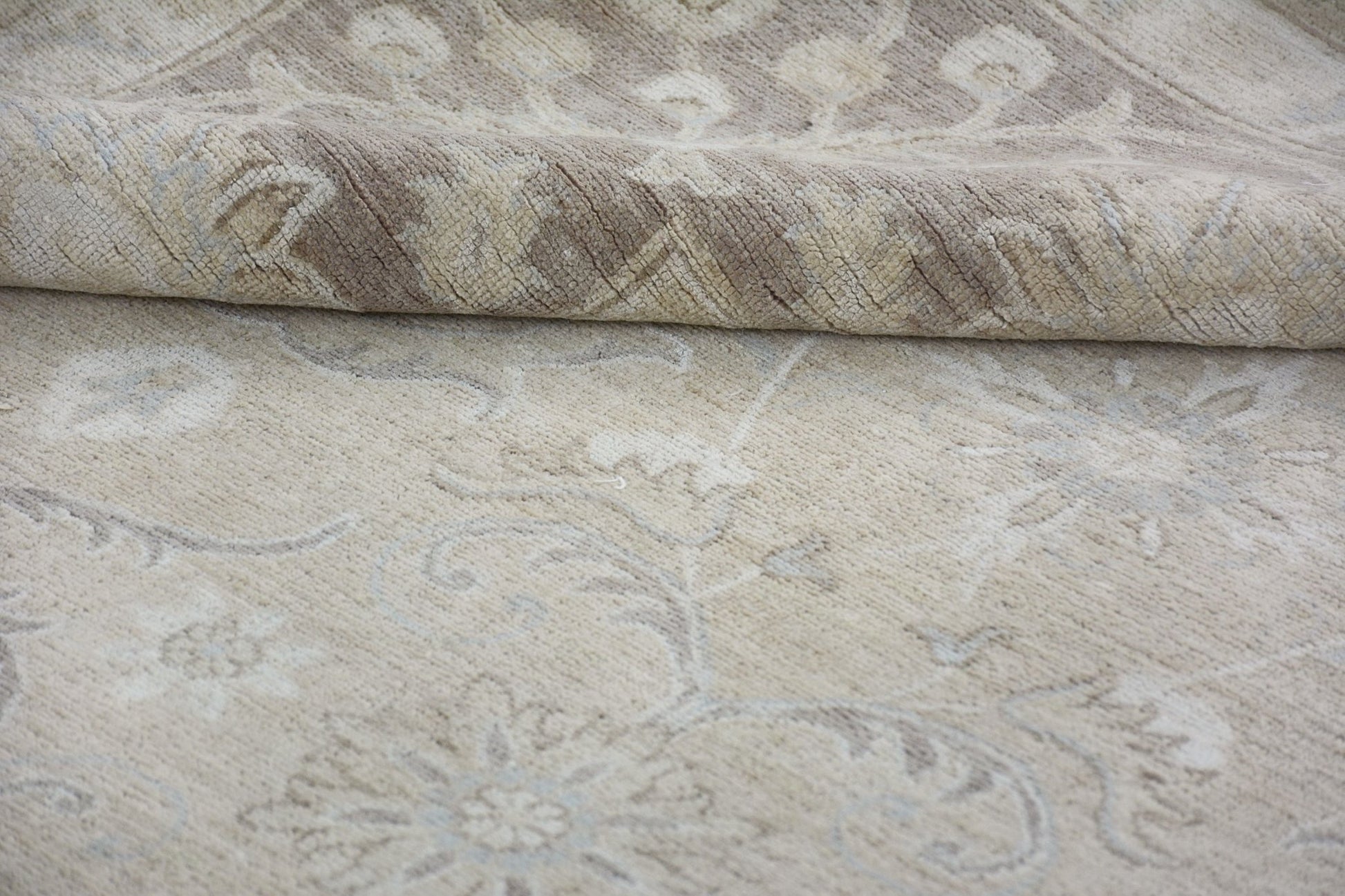 A handmade Afghan Chobi rug featuring a traditional floral pattern in neutral beige tones.