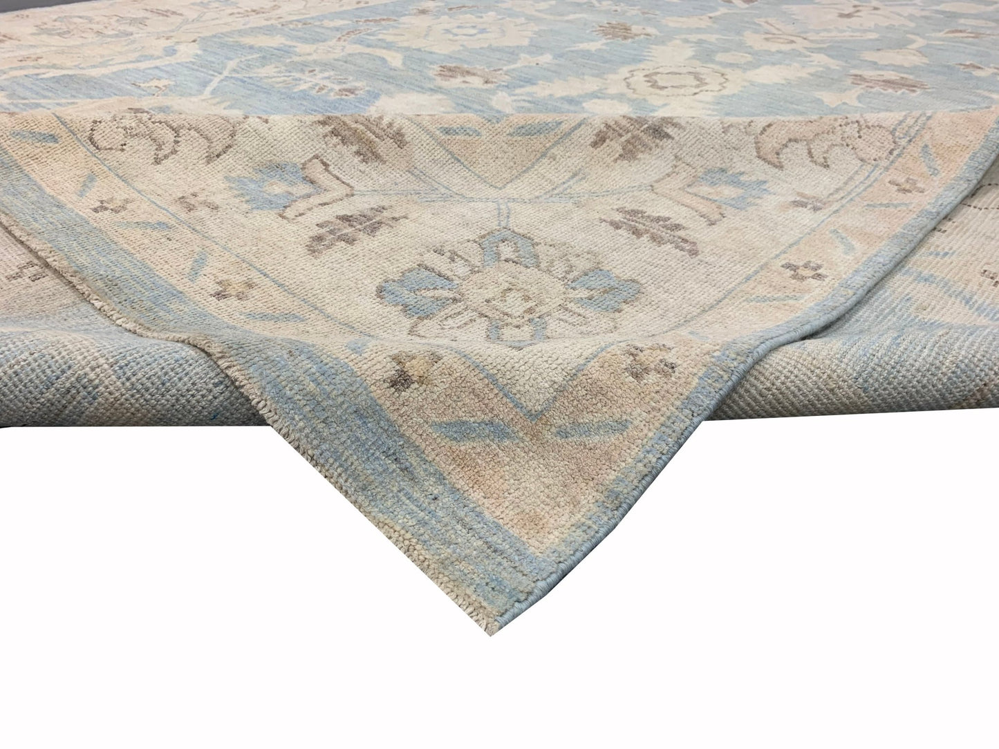 A handmade Afghan Chobi rug featuring a traditional floral pattern in soft blue and beige tones.