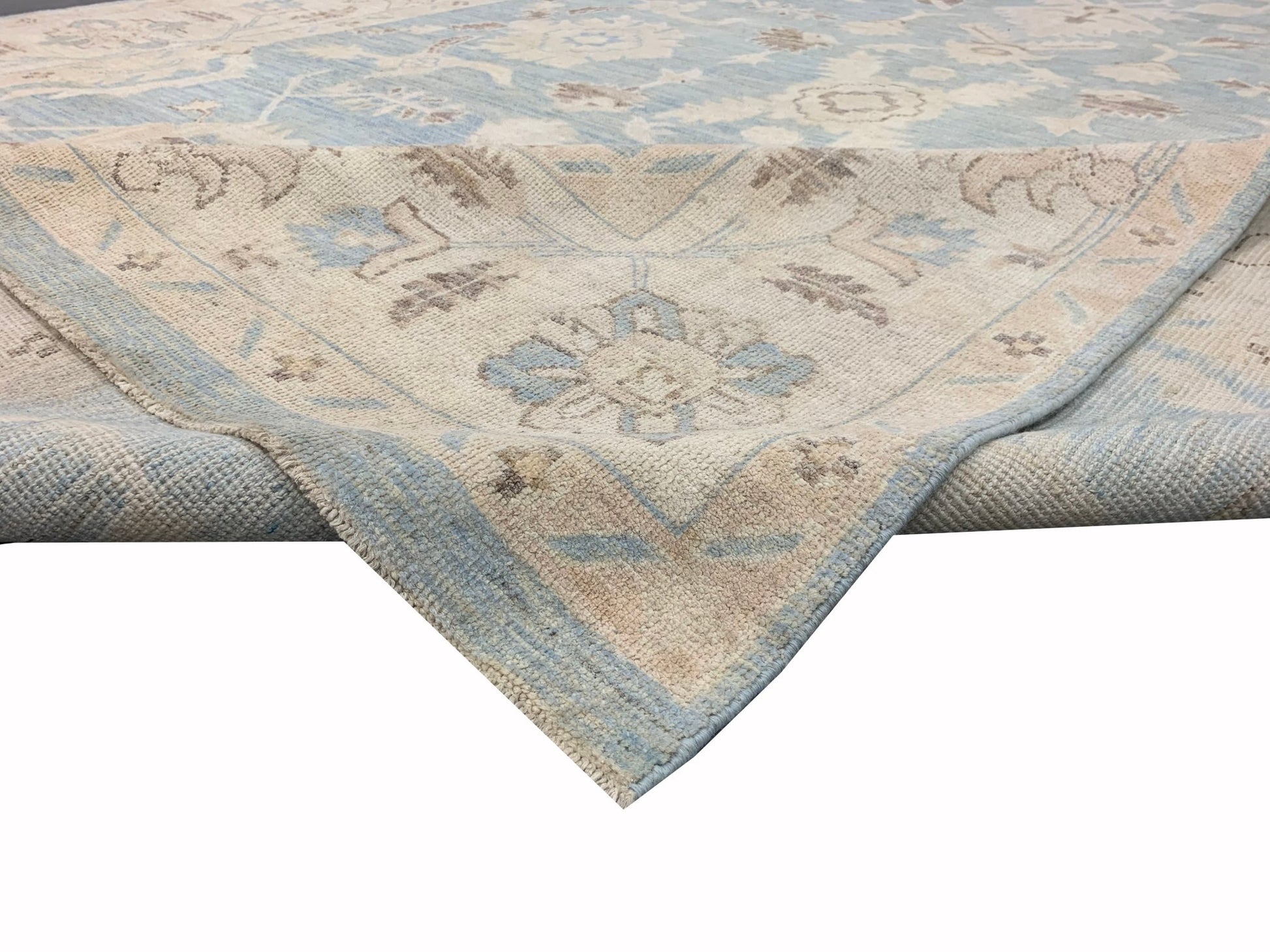 A handmade Afghan Chobi rug featuring a traditional floral pattern in soft blue and beige tones.