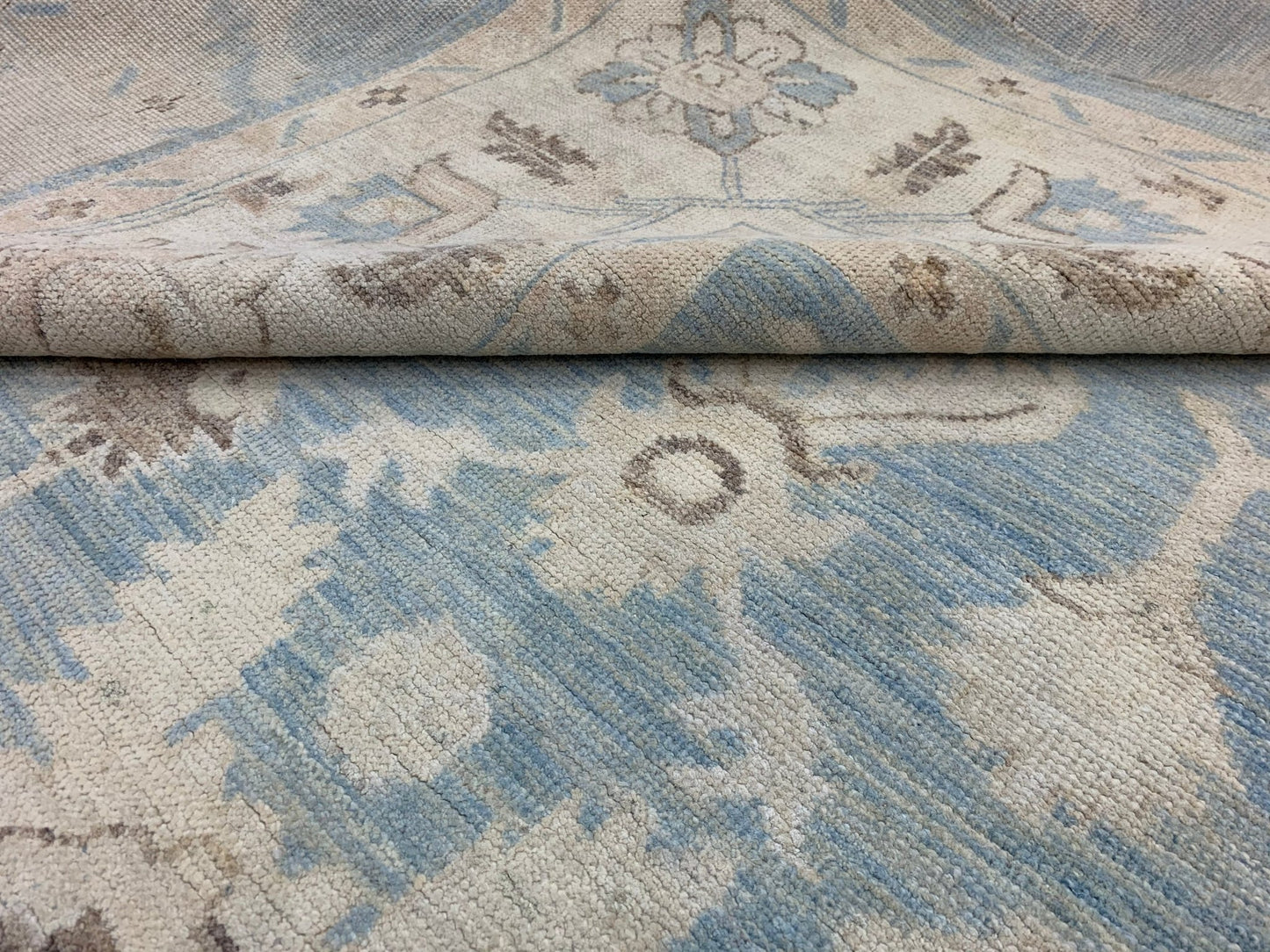 A handmade Afghan Chobi rug featuring a traditional floral pattern in shades of blue and beige.