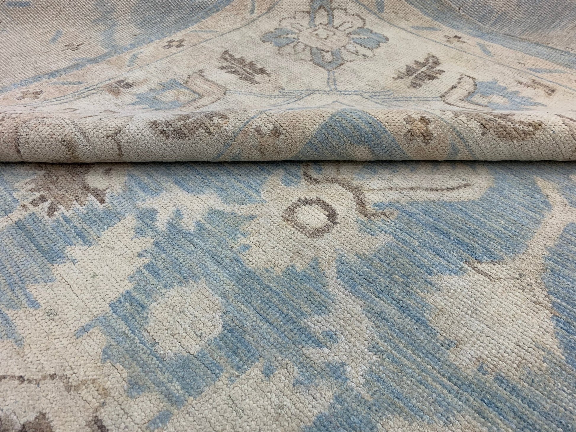 A handmade Afghan Chobi rug featuring a traditional floral pattern in shades of blue and beige.