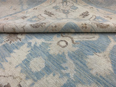 A handmade Afghan Chobi rug featuring a traditional floral pattern in shades of blue and beige.