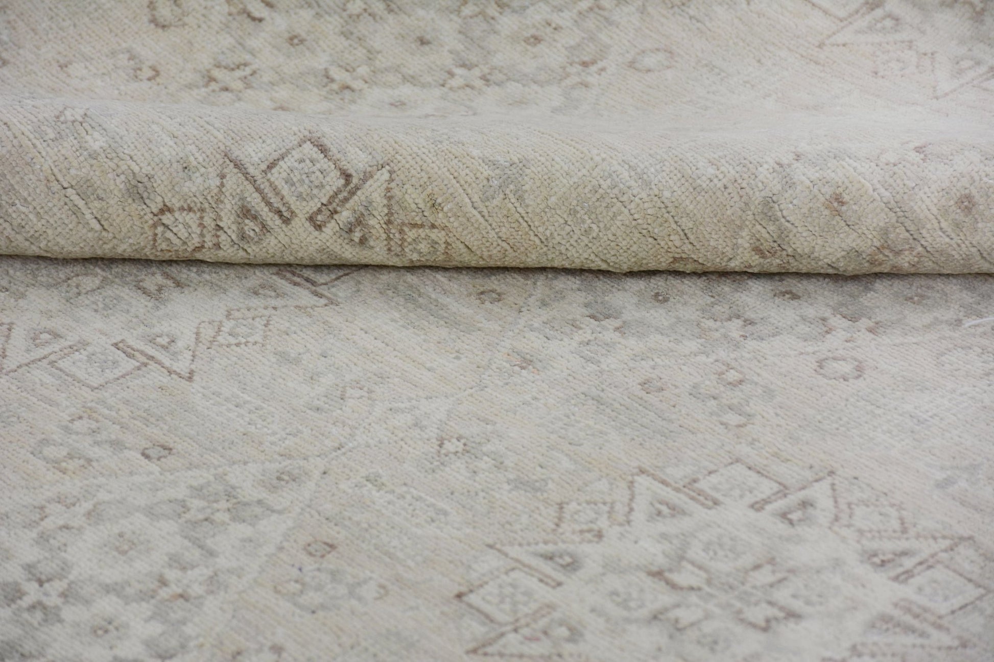 A handmade Afghan Chobi rug featuring a neutral cream palette with subtle geometric patterns.