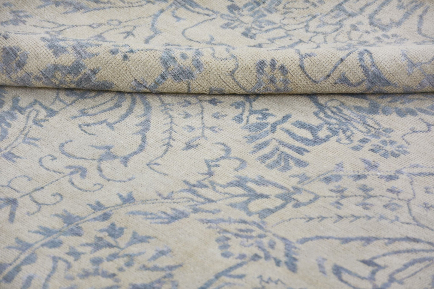 A handmade Afghan Chobi rug featuring a blue floral pattern on a cream wool background.