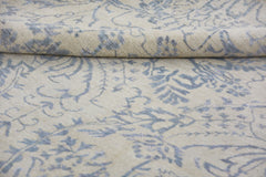 A handmade Afghan Chobi rug featuring a blue floral pattern on a cream wool background.
