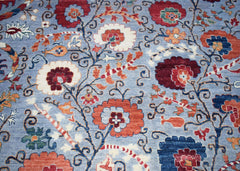 An Afghan Chobi rug featuring a traditional floral pattern in red, orange, and blue on a blue base.