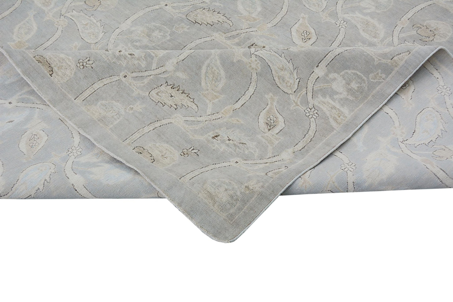 A handmade Afghan Chobi rug featuring a light grey floral pattern with a folded corner.
