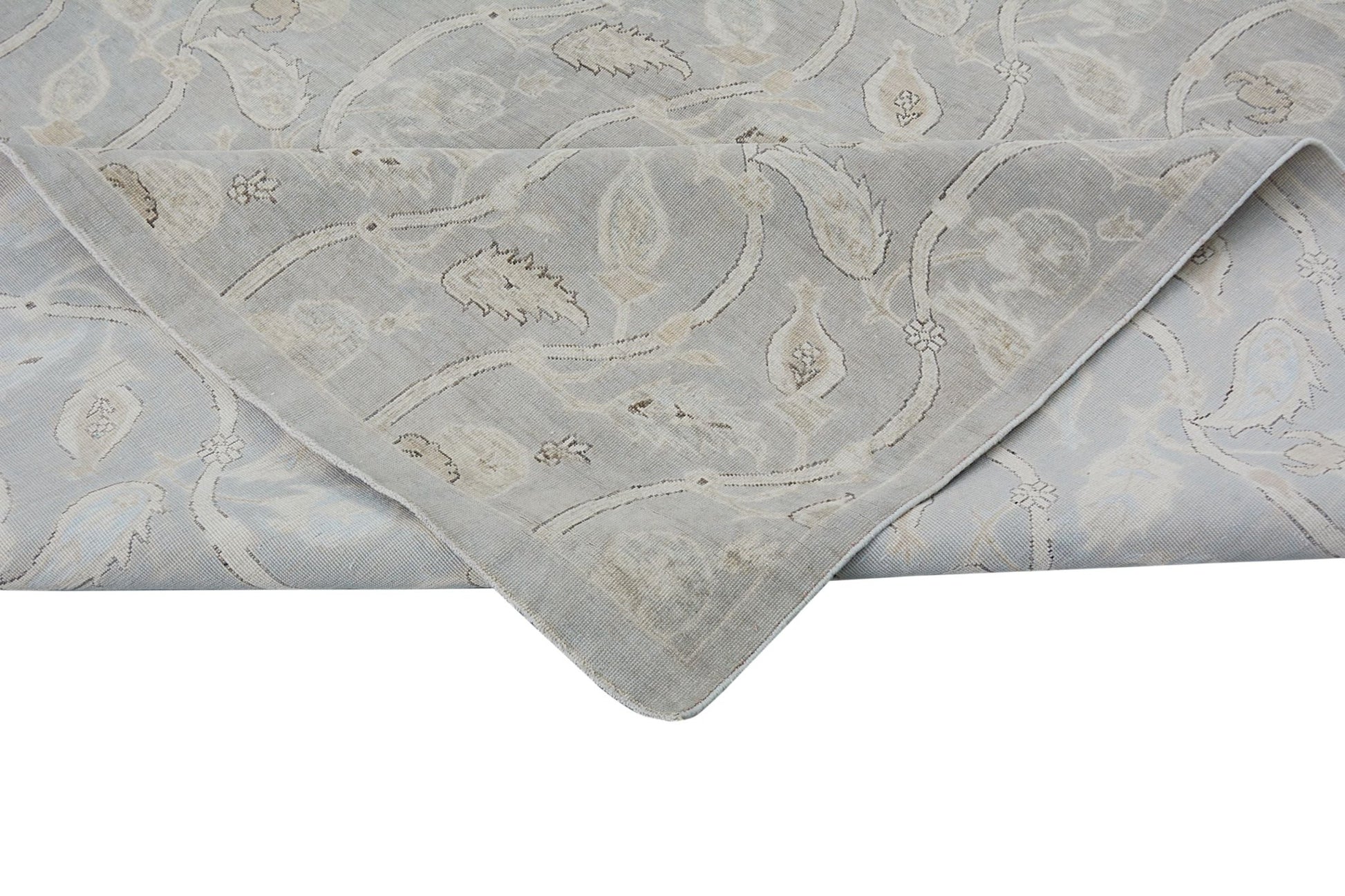 A handmade Afghan Chobi rug featuring a light grey floral pattern with a folded corner.
