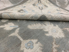 A handmade Afghan Chobi rug featuring a traditional floral pattern in shades of grey and blue.