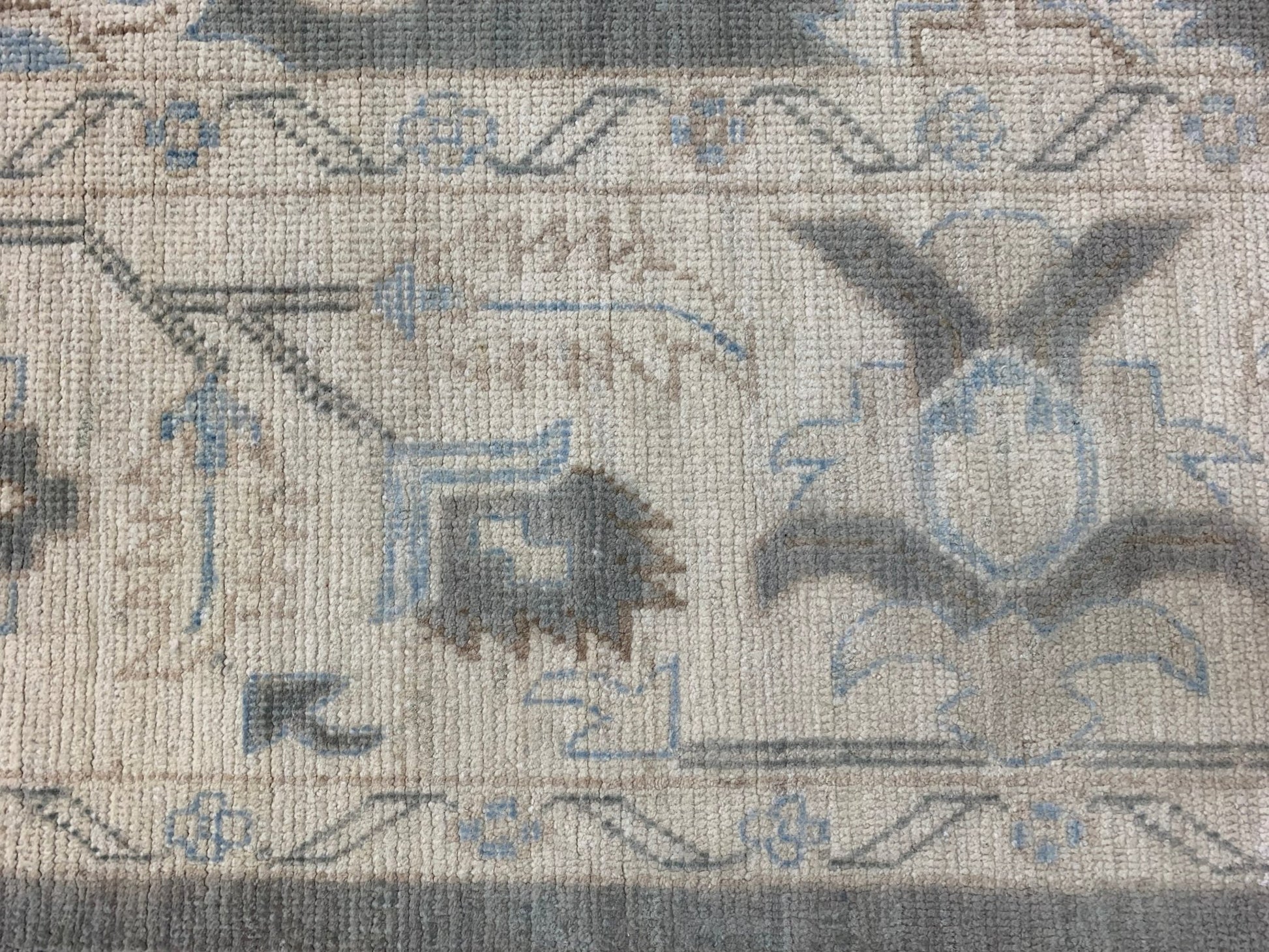 A close-up of an Afghan Chobi rug featuring traditional floral patterns in blue and grey tones.