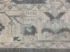 A close-up of an Afghan Chobi rug featuring traditional floral patterns in blue and grey tones.