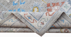 A handwoven Afghan Chobi rug featuring a traditional floral pattern in soft blue, red, and grey.
