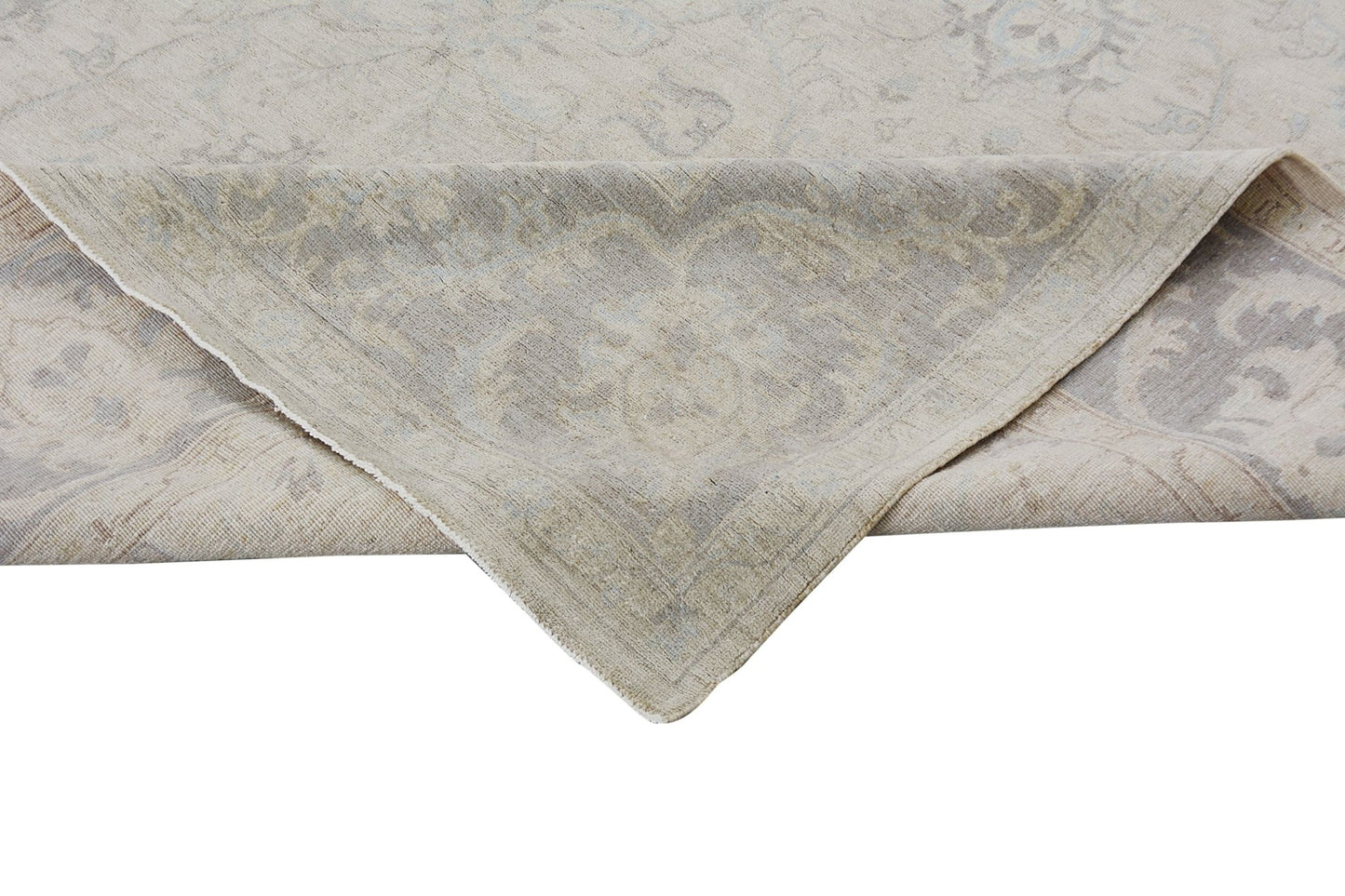 A corner of a handmade Afghan Chobi rug with a light beige and grey traditional floral pattern.